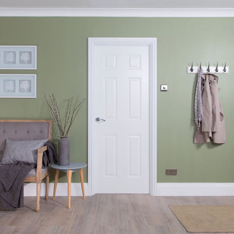 Living room with green walls, a white 6-panel smooth door, and a gray sofa.