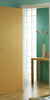 A light oak door in a room with teal walls, a chair, and a small table.