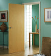 A light oak door in a room with teal walls, a chair, and a small table.