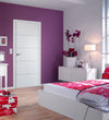 Modern bedroom with white door, purple walls, floral bedding, and a clear chair.